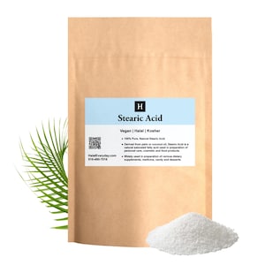 May include: A brown paper bag with a blue label that reads "Stearic Acid". A pile of white, granular powder sits in front of the bag. The text on the label indicates the product is vegan, halal, and kosher.