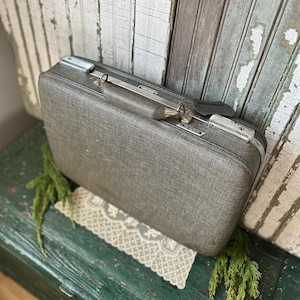 American Tourister tri-taper koffer uit het midden van de eeuw, grijze kleur, bagagelabel