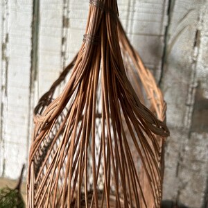 May include: A tall, woven wicker basket with a rounded top and a flared base. The basket is made of light brown wicker and has a natural, rustic appearance. The wicker is tightly woven, creating a sturdy structure. The basket is ideal for storage or decoration.