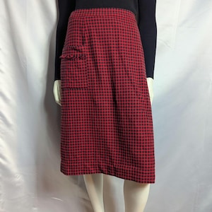 May include: A knee-length skirt featuring a red and black checkered pattern. The skirt has a straight silhouette and includes a single patch pocket on the right side with a frayed, raw-edge detail along the top opening of the pocket.