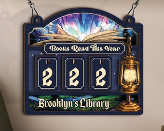 Może przedstawiać: Granatowy drewniany znak z napisem "Books Read This Year" i "Brooklyn's Library". Znak ma ilustrację latarni i książki. Na znaku wyświetlane są liczby "222".