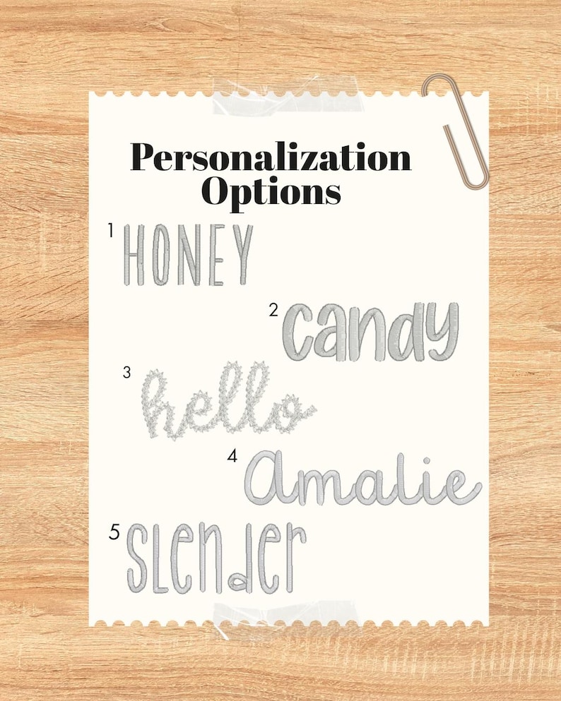May include: A white paper with the text "Personalization Options" and five examples of personalized text: "HONEY", "candy", "hello", "Amalie", and "SLENDER". A paperclip is attached to the top right corner.