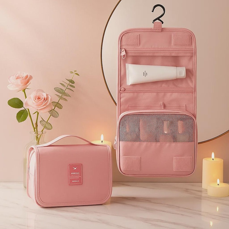 K&ouml;nnte beinhalten: Eine rosa Kosmetiktasche und ein h&auml;ngender Kulturbeutel. Der Organizer hat mehrere F&auml;cher und eine Netztasche. Eine Tube Produkt ist in einem der F&auml;cher sichtbar. Die Tasche hat einen Griff und ein Etikett.