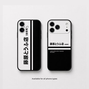 Op de afbeelding: Twee zwart-witte telefoonhoesjes met Japanse tekst die Fujiwara Tofu Shop leest. Het linker hoesje heeft een verticaal gespleten ontwerp, terwijl het rechter hoesje de tekst horizontaal weergeeft met AE86 Sprinter Trueno GT-APEX eronder.
