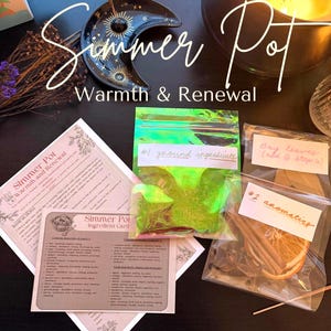 Peut inclure: Un ensemble d'articles pour un pot à mijoter, comprenant des cartes d'ingrédients, un plat en forme de croissant de lune et des sachets étiquetés "#1 ground ingredients" et "#2 aromatics." Le texte "Simmer Pot Warmth & Renewal" est affiché.