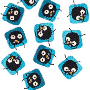 Puede incluir: Una colección de cuadrados de ganchillo con un personaje negro con grandes ojos blancos y una expresión sonriente. El personaje está rodeado por un borde cuadrado azul y pequeños detalles florales. Los cuadrados están dispuestos sobre un fondo blanco.