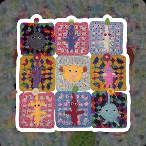 May include: A colorful, handmade crochet blanket featuring nine squares, each with a different Pikmin character. The squares are bordered in white and set against a multicolored background. The Pikmin are in various colors, including gray, blue, and yellow.