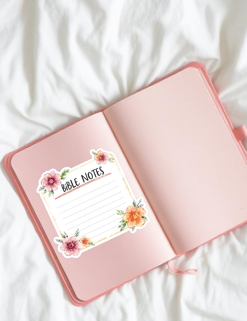 May include: Open pink journal with a floral sticker that reads "Bible Notes." The sticker has a white background with lines for writing and is decorated with watercolor flowers in shades of pink, orange, and yellow.