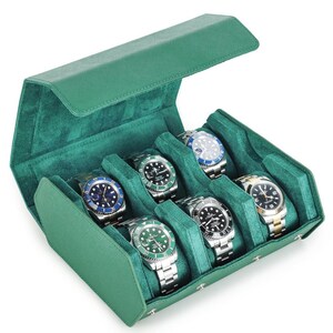 May include: A green leather watch case with a velvet interior, holding seven wristwatches. The watches have silver and gold bands, with black, blue, and green watch faces. The case is open, revealing the watches.