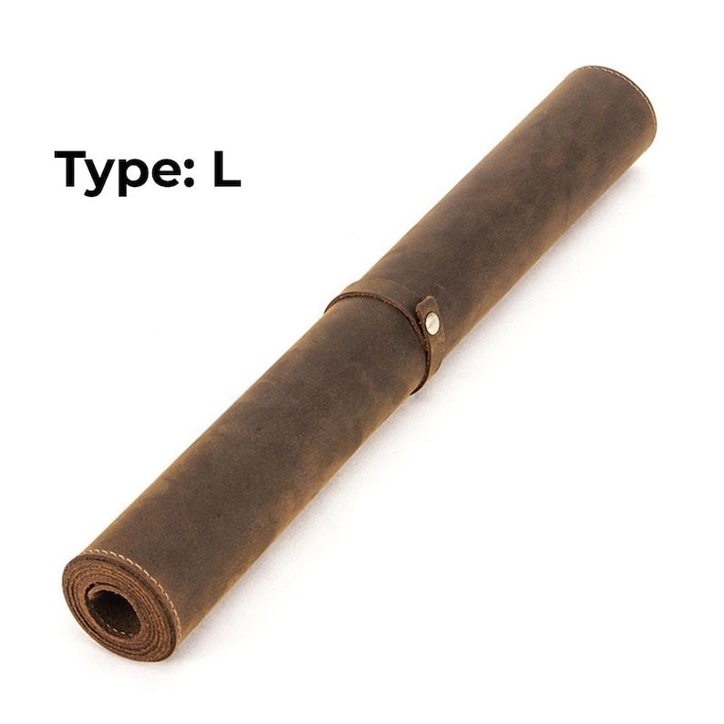 May include: Rolled brown leather desk mat with a strap and button closure. The mat is labeled "Type: L" in black text. The leather has a distressed appearance.