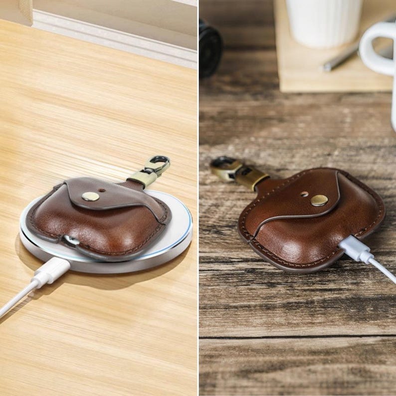 May include: A brown leather case with a gold-colored clasp and a small flap, designed to hold a small electronic device. The case is shown on a white wireless charging pad and also plugged in with a white charging cable.