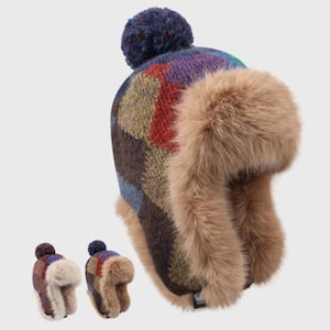 May include: A winter hat with a colorful plaid pattern in shades of blue, purple, red, and brown. The hat features faux fur ear flaps and a matching pom-pom on top. Two smaller versions of the hat are also shown.
