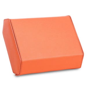 May include: A rectangular, coral-colored box with a slightly textured surface. The box has a hinged lid and is stitched along the edges. The box is made of a solid material and is set against a white background.