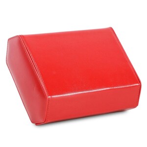 May include: A bright red, rectangular box with a slightly angled top. The box appears to be made of a smooth, possibly leather-like material, with visible stitching along the edges. The overall design is simple and modern.