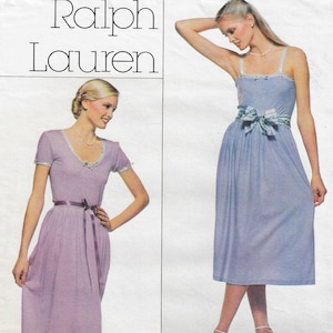 May include: Two women wearing long, light-colored dresses. The woman on the left is wearing a lavender dress with a thin, purple ribbon tied at the waist. The woman on the right is wearing a light blue dress with a green and white patterned ribbon tied at the waist. Both women are wearing white sandals.