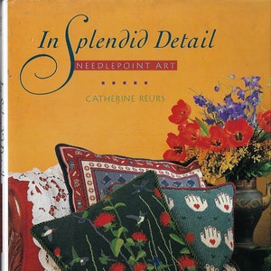 May include: A book titled "In Splendid Detail: Needlepoint Art" by Catherine Reurs, featuring a close-up of needlepoint pillows with floral and hummingbird designs.