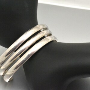 May include: A silver bangle bracelet with three bands.