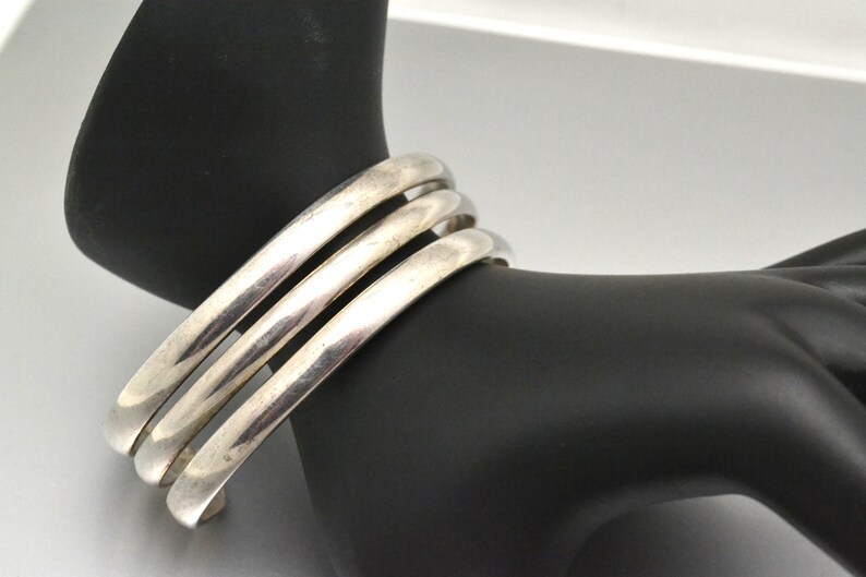 May include: A silver bangle bracelet with three bands.