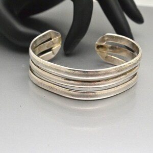 May include: A silver bangle bracelet with three bands.