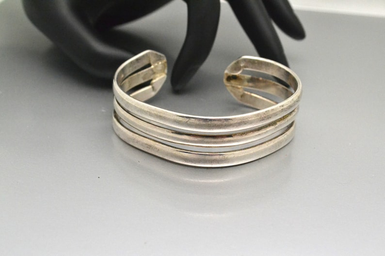 May include: A silver bangle bracelet with three bands.
