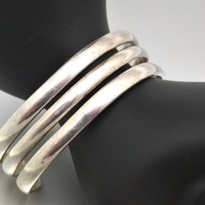 May include: A silver bangle bracelet with three bands.