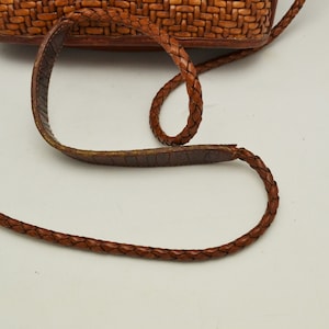 Puede incluir: Bolso bandolera de cuero marr&oacute;n con una textura tejida en el cuerpo principal. El bolso cuenta con una correa de cuero trenzado y una almohadilla para el hombro. El bolso est&aacute; dise&ntilde;ado para llevar lo esencial y tiene un estilo cl&aacute;sico y atemporal.