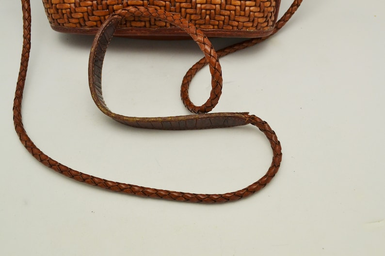 Puede incluir: Bolso bandolera de cuero marr&oacute;n con una textura tejida en el cuerpo principal. El bolso cuenta con una correa de cuero trenzado y una almohadilla para el hombro. El bolso est&aacute; dise&ntilde;ado para llevar lo esencial y tiene un estilo cl&aacute;sico y atemporal.