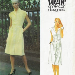 Op de afbeelding: Een vrouw draagt een lichtgele button-down jurk met bijpassende riem en zwarte hakken. De jurk heeft korte mouwen en een knielange rok. De afbeelding bevat ook een Vogue American Designers logo.