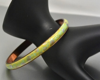 May include: A copper bangle bracelet with a yellow enamel finish and a light blue and white speckled pattern.