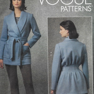 May include: A light blue coat with a wrap-around belt, pockets, and a shawl collar. The image also shows the back of the coat. The text "VOGUE PATTERNS" is visible in the upper right corner.