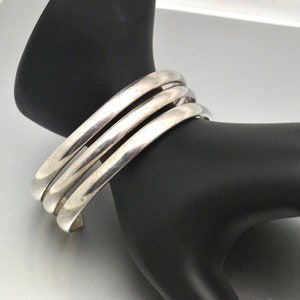 May include: A silver bangle bracelet with three bands.