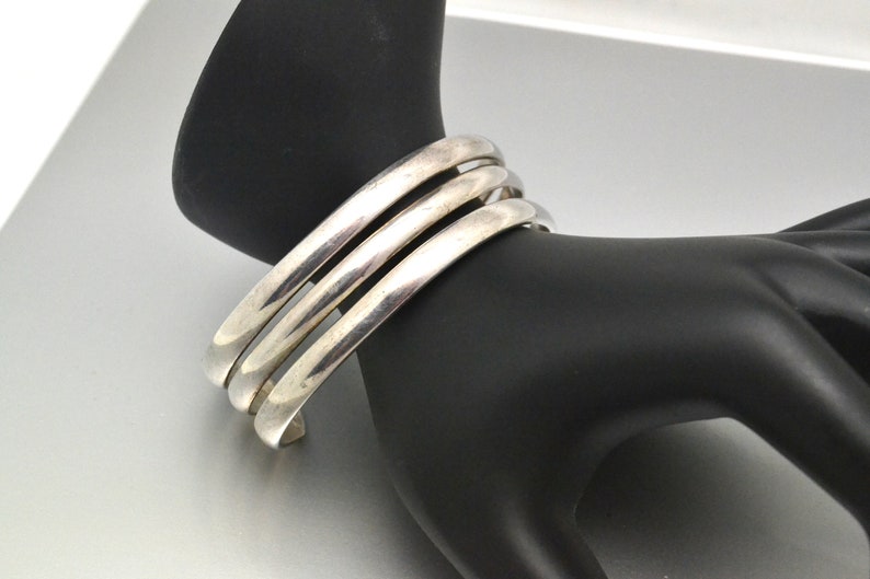 May include: A silver bangle bracelet with three bands.