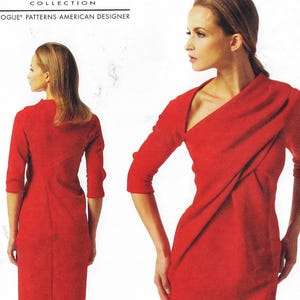 May include: A red dress with a diagonal neckline and a fitted silhouette. The dress has a long sleeve and a gathered detail at the waist. The dress is shown on a model with a white background.