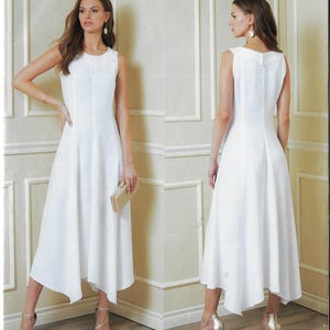 May include: A sleeveless white dress with a midi-length asymmetrical hemline. The dress features a round neckline and a fitted bodice that flows into a flared skirt. The model is holding a gold clutch and wearing gold heels.