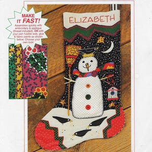 May include: A black fabric Christmas stocking featuring a white snowman with three buttons, a broom, and a birdhouse. The name ELIZABETH is embroidered at the top. The design includes a crescent moon, stars, and three black birds at the bottom.