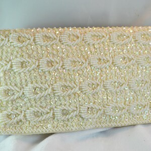 Op de afbeelding: Een witte parel clutch met een geometrisch patroon. De clutch is gemaakt van kleine, iriserende parels en pailletten.
