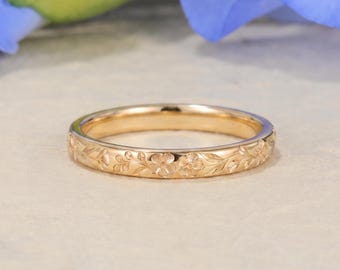 Può includere: Un anello in oro caratterizzato da un motivo floreale inciso in modo continuo lungo tutta la fascia esterna. Il metallo presenta una finitura lucida e il design è composto da piccoli fiori ripetuti e foglie delicate incise sull'anello.
