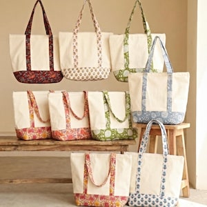 Peut inclure: Plusieurs sacs fourre-tout en toile avec des motifs floraux et imprimés. Les sacs ont des corps crème, des bases à motifs colorés et des poignées assorties. Certains sont suspendus, d'autres sont sur un banc et un tabouret en bois.