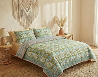 May include: A bed with a green floral patterned quilt and matching pillowcases. The quilt has a blue and white floral design with a pink border. A woven macrame wall hanging is above the bed, and a woven side table with a lamp is on the left.