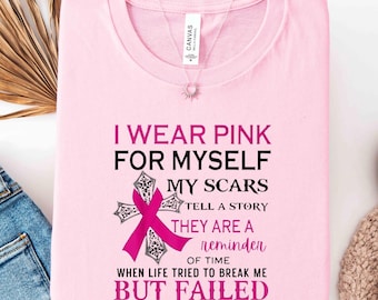 May include: A light pink t-shirt featuring black and dark pink text that reads I WEAR PINK FOR MYSELF MY SCARS TELL A STORY THEY ARE A REMINDER OF TIME WHEN LIFE TRIED TO BREAK ME BUT FAILED BREAST CANCER AWARENESS with a cross and pink ribbon.