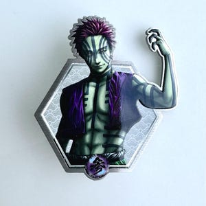 May include: A hexagonal metal pin featuring a character with green skin, purple hair, and black markings. The character is wearing a purple garment and has a Japanese symbol at the bottom. The pin has a silver border.