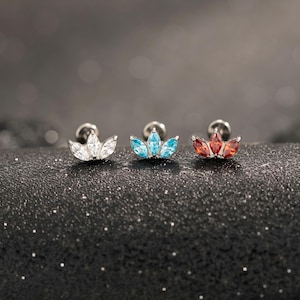 May include: Three stud earrings featuring a crown-like design with marquise-cut stones. The left earring has clear stones, the center has light blue stones, and the right has deep red stones, all set in a metallic base with a post backing.