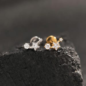 Peut inclure: Deux boucles d'oreilles à tige au motif céleste, composées d'une pierre ronde transparente et d'une pierre en forme d'étoile. L'une est argentée et l'autre dorée. Chaque bijou possède un fermoir à tige et une petite étoile à l'extrémité.