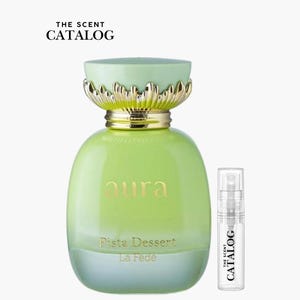 May include: A green perfume bottle with a gold-colored top and a small sample bottle. The perfume bottle has the word "aura" in gold lettering and the words "Fista Dessert La Fede" below it. The sample bottle has the words "THE SCENT CATALOG" on it.
