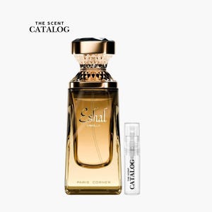 May include: A perfume bottle with a gold cap and a clear glass body, labeled "Eshal Vanilla." A smaller sample bottle is next to it. The text "The Scent Catalog" is at the top, and "Paris Corner" is at the bottom.
