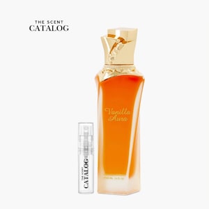 May include: A perfume bottle with a gold cap and a vanilla-colored liquid inside. The bottle is labeled "Vanilla Aura" and is accompanied by a smaller sample bottle. The text "THE SCENT CATALOG" is visible.