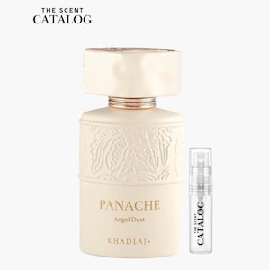 May include: A cream-colored perfume bottle with a gold-colored band and a matching cap. The bottle is embossed with a floral design and the words "PANACHE Angel Dust" are printed on the front. A small sample bottle is next to it. The text "THE SCENT CATALOG" is at the top.