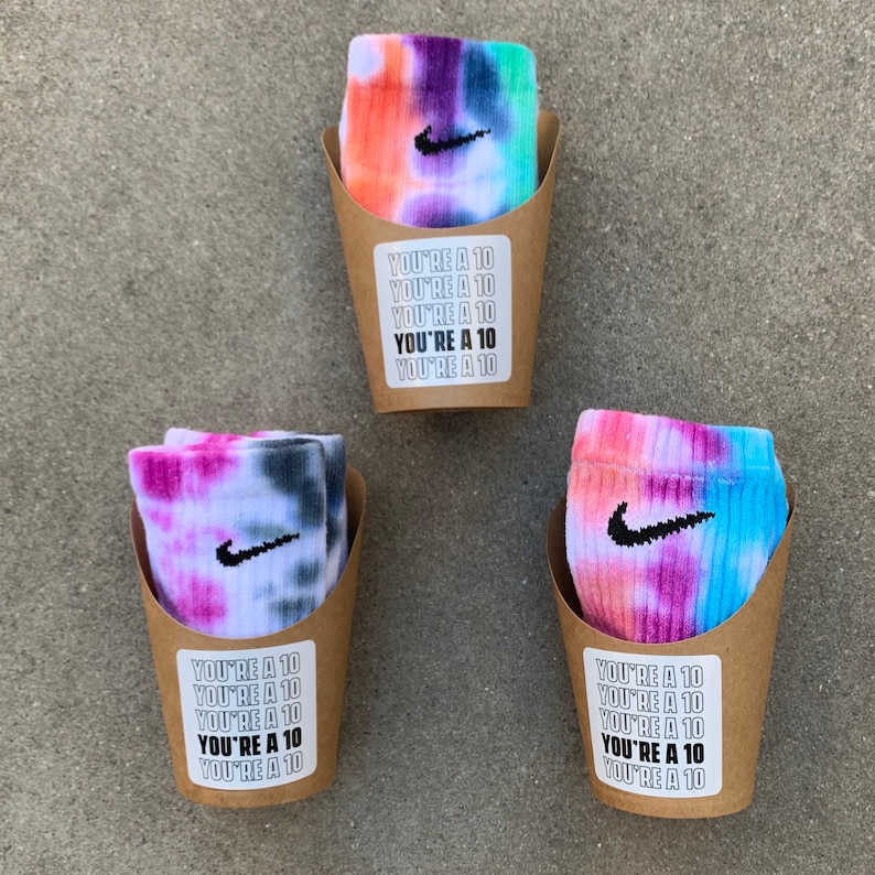 May include: Three pairs of tie-dye socks with a Nike swoosh logo in brown paper cups with the text "You're a 10" repeated on the front.