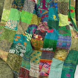 May include: A patchwork quilt with a variety of green, yellow, and purple fabrics. The quilt is made of squares and rectangles of different patterns and textures. The edges are finished with a green border. The text "PrintBell" is visible.