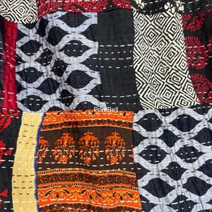 Pode incluir: Um t&ecirc;xtil de patchwork com uma variedade de padr&otilde;es e cores. O design inclui formas geom&eacute;tricas, motivos florais e padr&otilde;es paisley em tons de preto, vermelho, laranja e branco. As pe&ccedil;as s&atilde;o costuradas com linha branca.